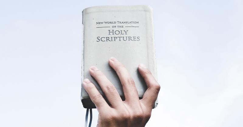 Hand holding the book: New World Translations of the Holy Scriptures