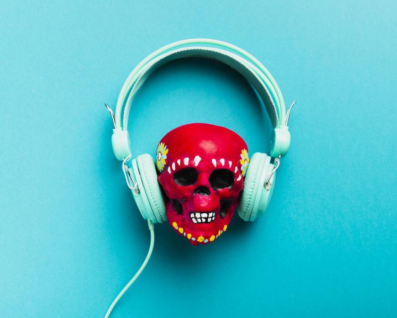 White Headphones around a small red toy-skull